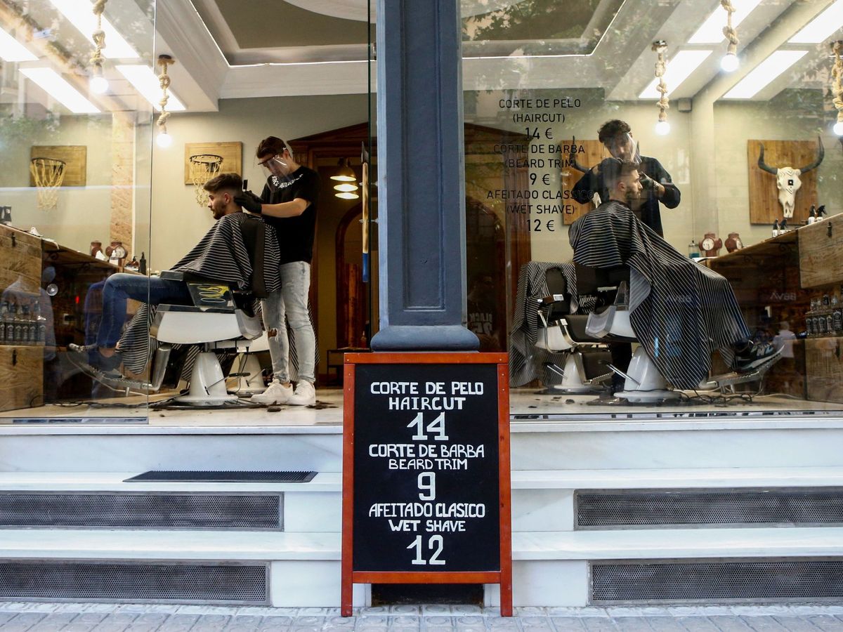 Foto: Dos peluqueros de una barbería del Eixample de Barcelona atienden a sendos clientes este lunes. (EFE)