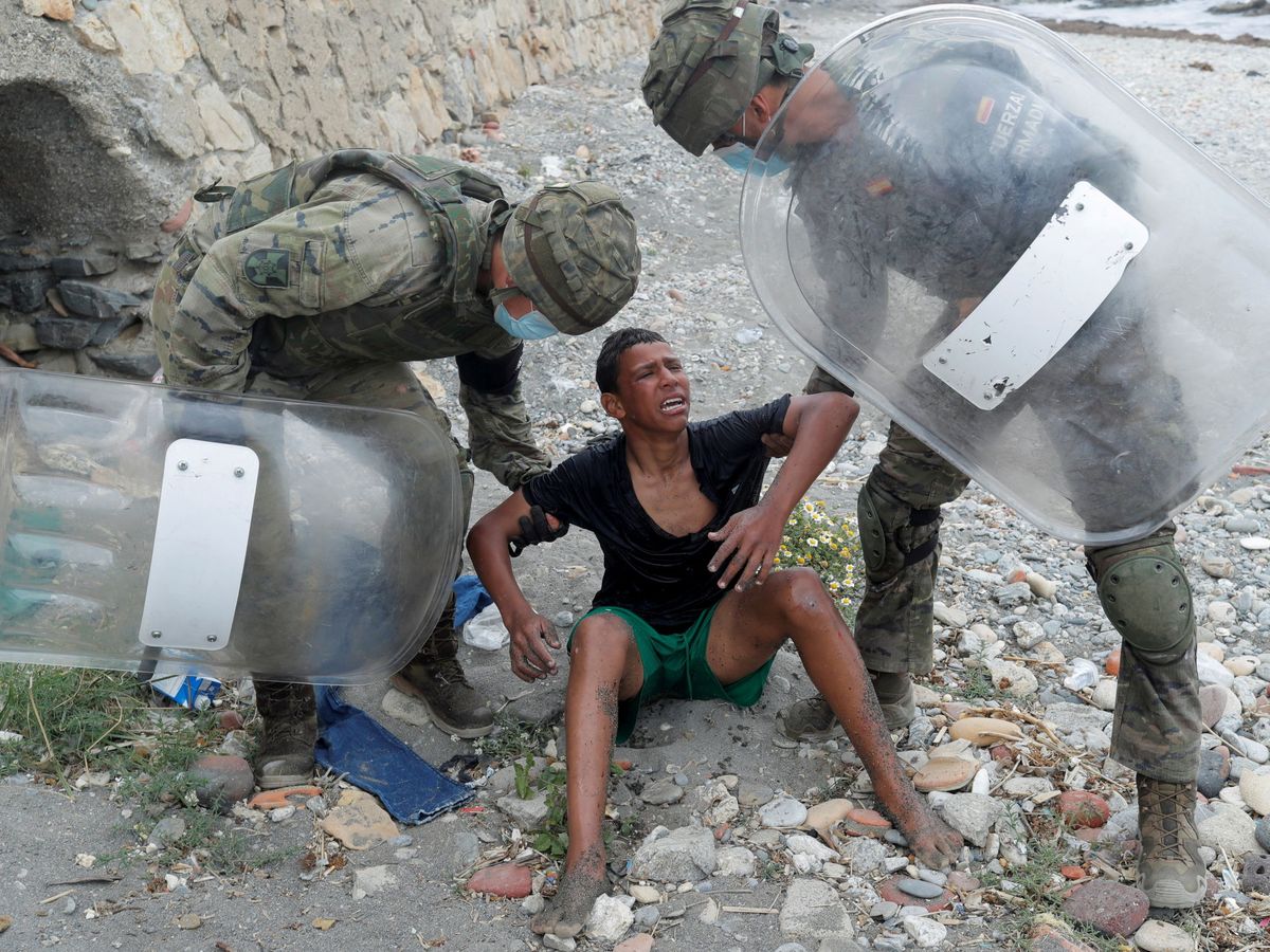Foto: Dos militares agarran a un niño que llega a Ceuta. (Reuters)