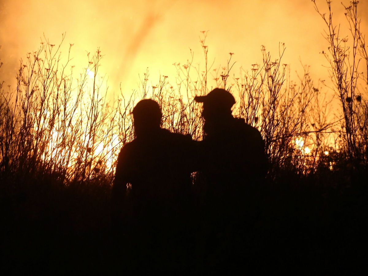 Foto: Dos personas frente a las llamas que están devorando Grecia. (EFE)