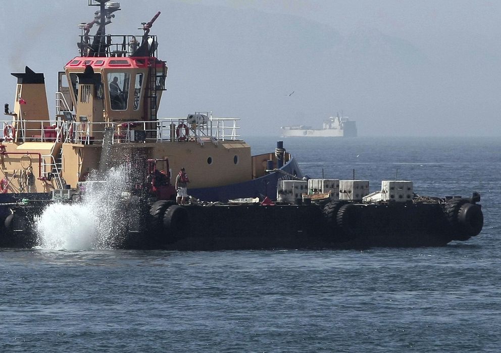 Foto: Un remolcador lanzando al mar bloques de hormigón en la zona donde suelen faenar los pesqueros españoles. (Efe)