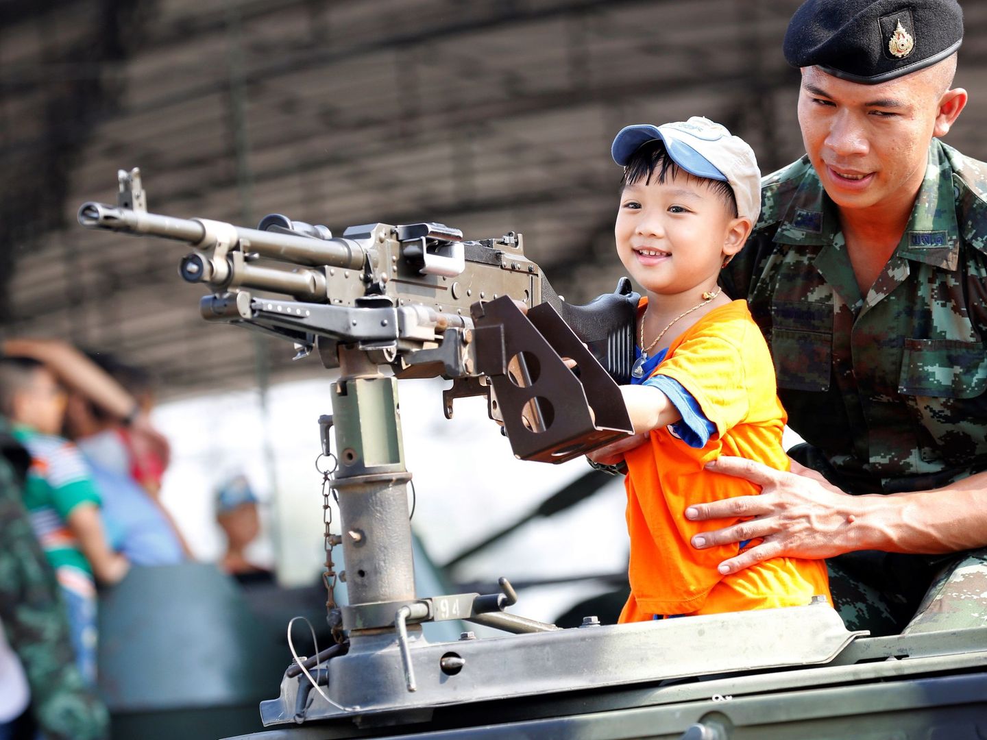 Un niño juega con la ametralladora de un tanque con ayuda de un militar durante el Día Nacional de los Niños en una base militar en Bangkok. (Reuters)