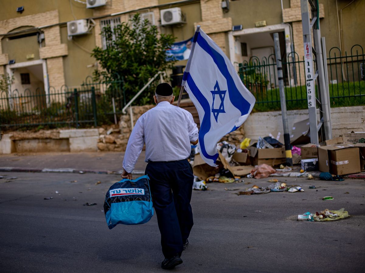 Foto: Un hombre camina con una bandera de Israel por las calles de Sderot. (EFE/Matin Divisek)