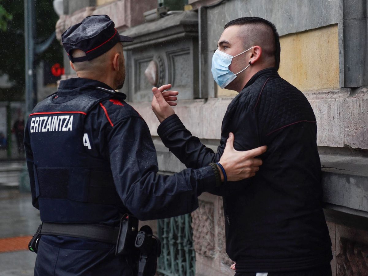 Foto: Un ertzaintza desaloja a un hombre de la plaza Moyua de Bilbao. (EFE)