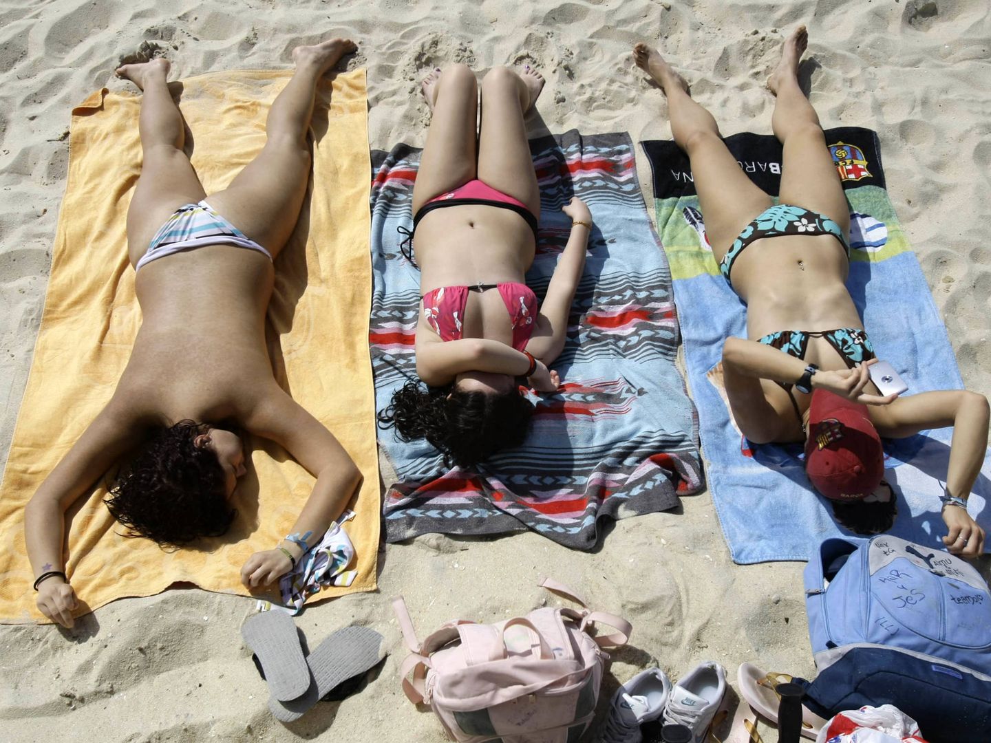 Tres mujeres toman el sol en la playa de Samil, en Vigo. (Reuters)