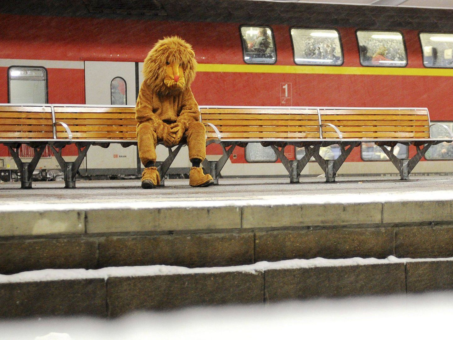 Un hombre, que se ha disfrazado de león, espera la llegada del tren en una estación. (EFE)