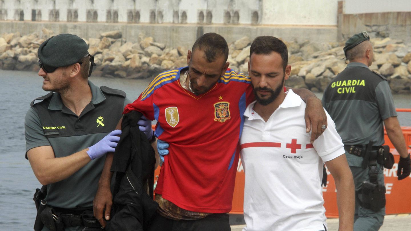 Un Guardia Civil y un miembro de Cruz Roja ayudan a uno de los inmigrantes rescatados. (EFE)