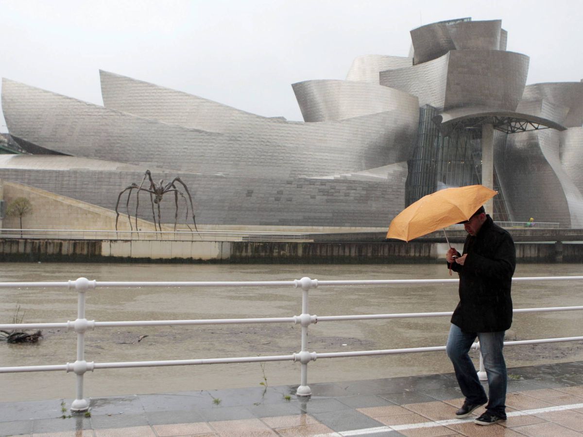 Foto: Un hombre camina en las proximidades del Museo Guggenheim junto a la ría de Bilbao en un día de fuertes lluvias. (EFE/Luis Tejido)