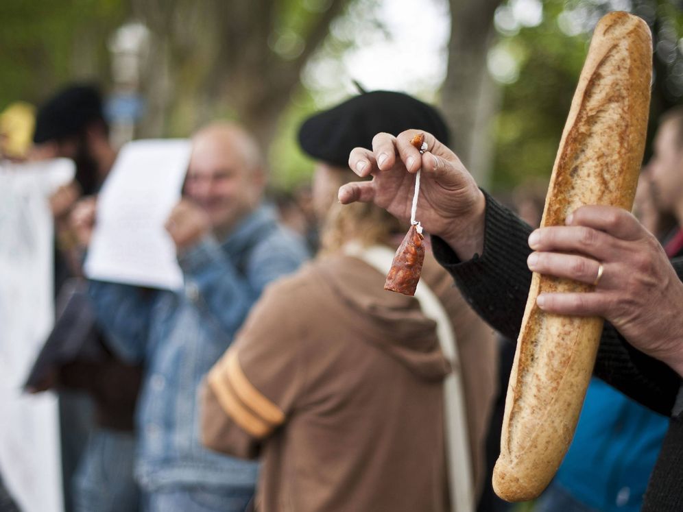 Foto: Un hombre sostiene en sus manos un chorizo y una barra de pan durante una protesta en Bilbao. (EFE)