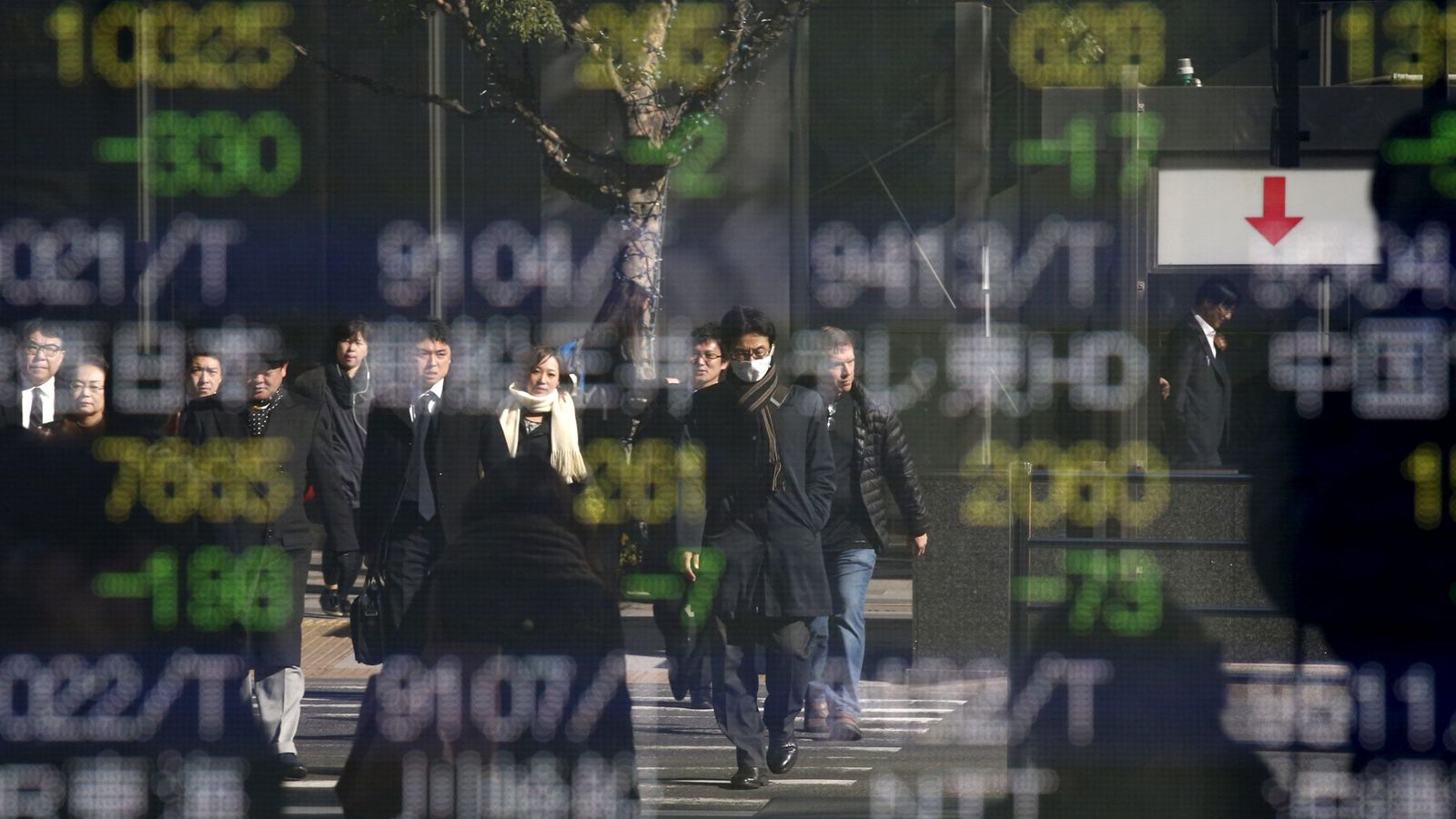 Foto: Varias personas se reflejan en un panel con cotizaciones de acciones en Tokio. (Reuters)