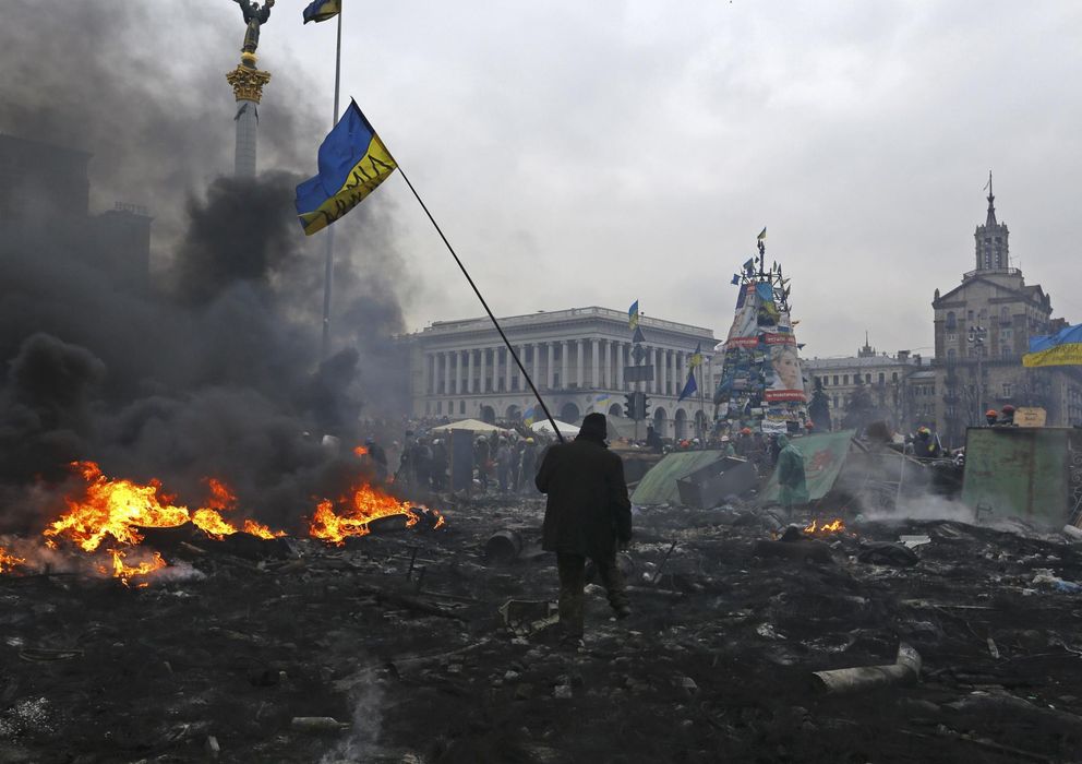 Foto: Un opositor con la bandera ucraniana camina entre los restos de los combates en la plaza de la Independencia de Kiev (Reuters).