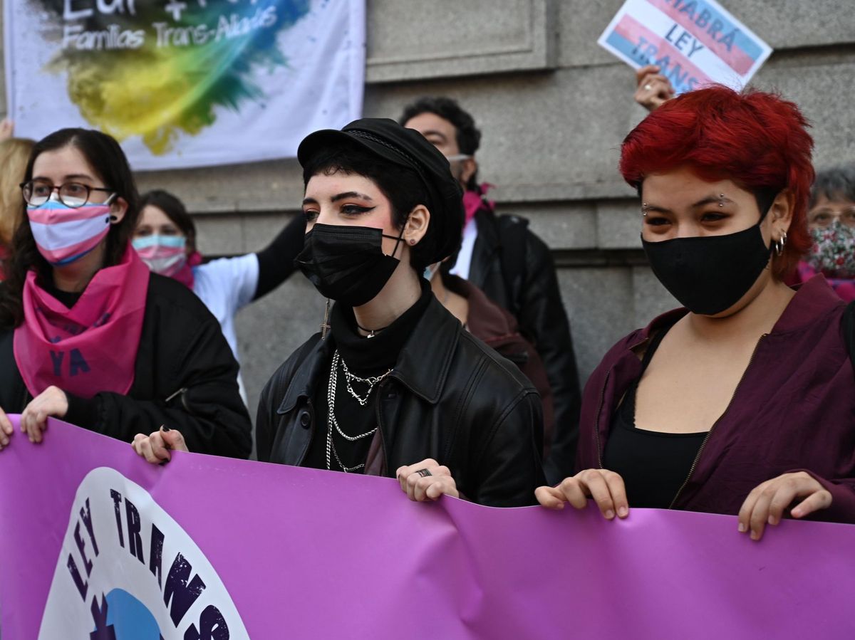 Foto: Decenas de personas en una concentración fente al Ministerio de Igualdad para demandar la aprobación urgente de la ley estatal trans. (EFE) 