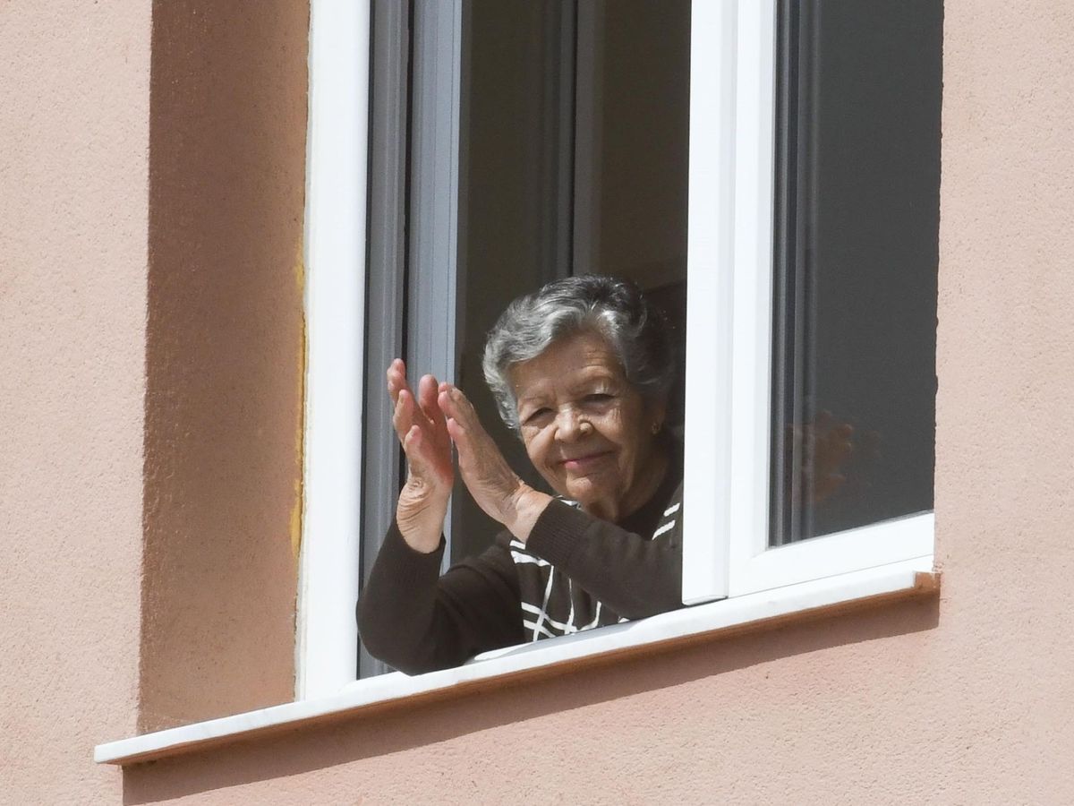 Foto: Una señora mayor aplaude desde una ventana de la residencia de mayores de Cájar (Granada) (EFE)