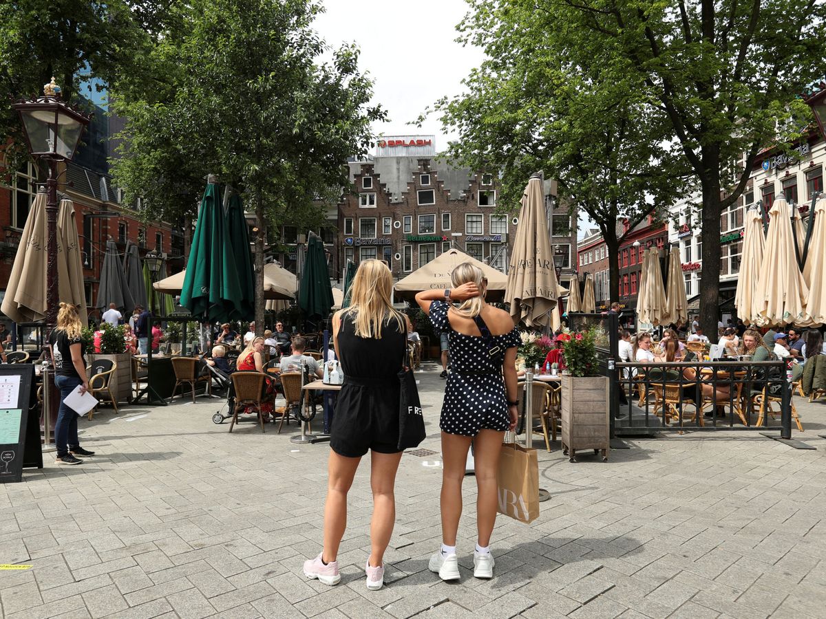 Foto: Unas mujeres esperan para sentarse frente a unos cafés en la plaza Leidseplein (Ámsterdam). (Reuters/Eva Plevier)