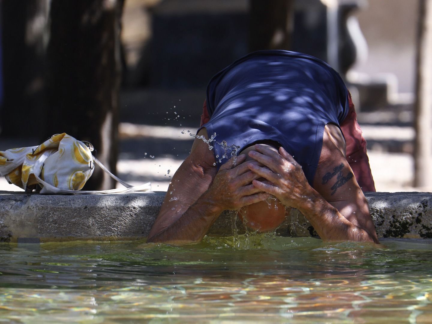 Un turista se refresca en la Fuente de los Naranjos de la mezquita-catedral de Córdoba. (EFE/Salas) 