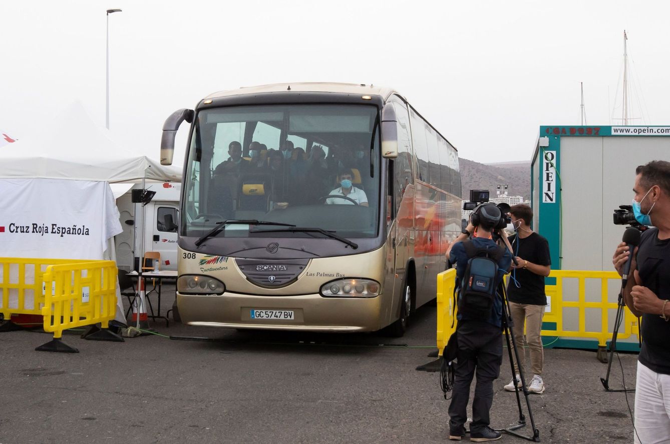 Un autocar deriva a inmigrantes desde el muelle de Arguineguín hacia un complejo hotelero. (EFE)
