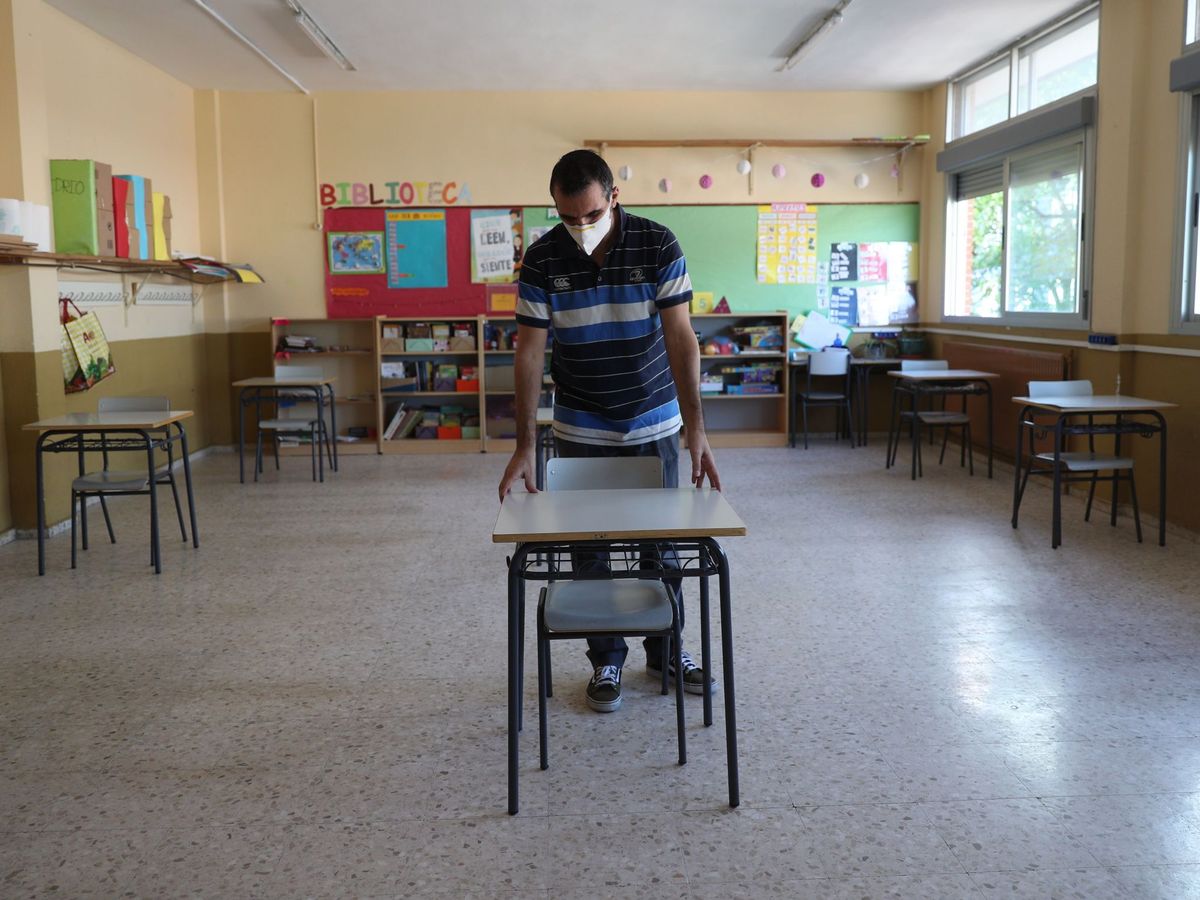 Foto: Un profesor separa la mesas de su aula, para favorecer la distancia social, en un colegio madrileño. (EFE)