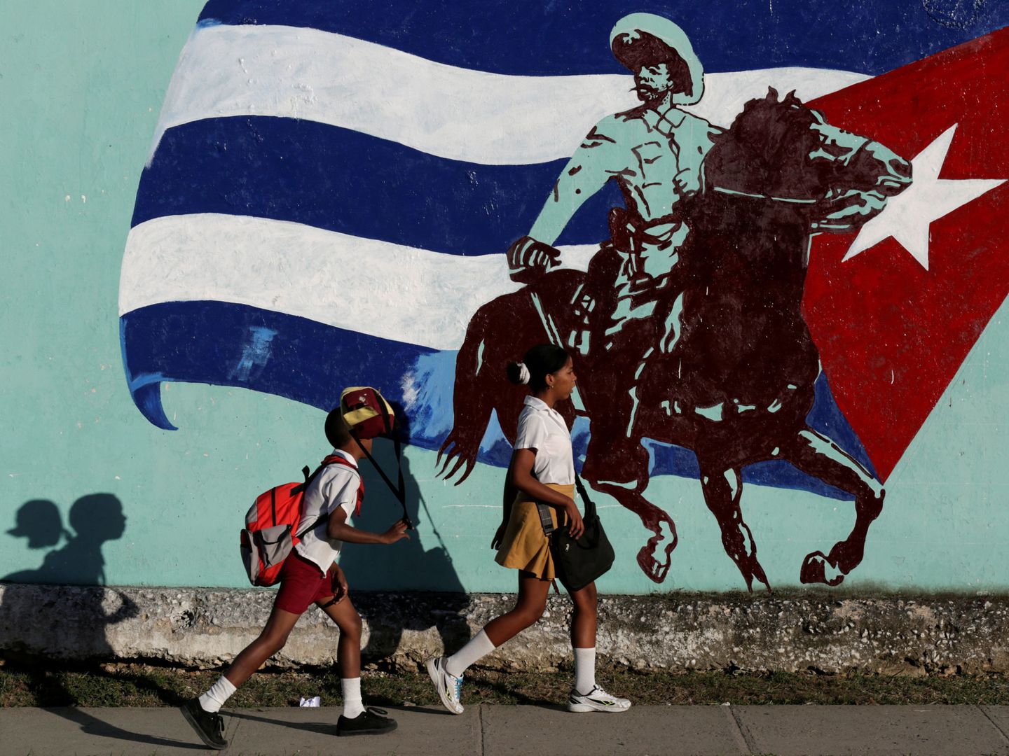Estudiantes cubanos pasan delante de un mural en La Habana, el 22 de noviembre de 2016 (Reuters)