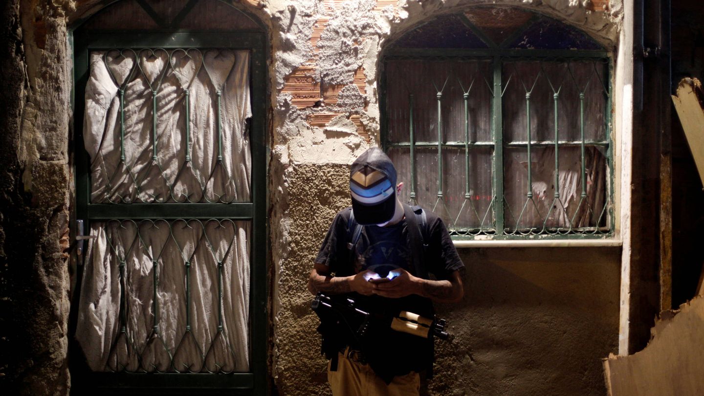 Un miembro de un grupo de narcotraficantes comprueba su móvil en un favela de Río. (Reuters)