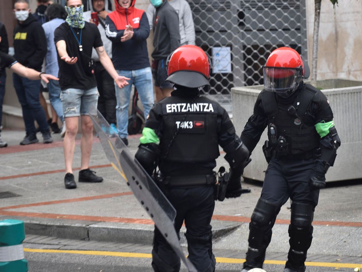 Dos agentes de la Ertzaintza apartan un balón y separan a los grupos radicales del mitin del partido. (EFE)