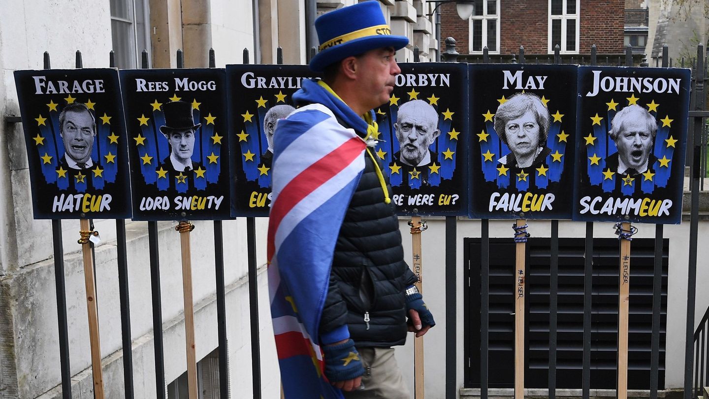 Un manifestante contrario al Brexit  camina junto a carteles que critican a políticos en Londres. (EFE)