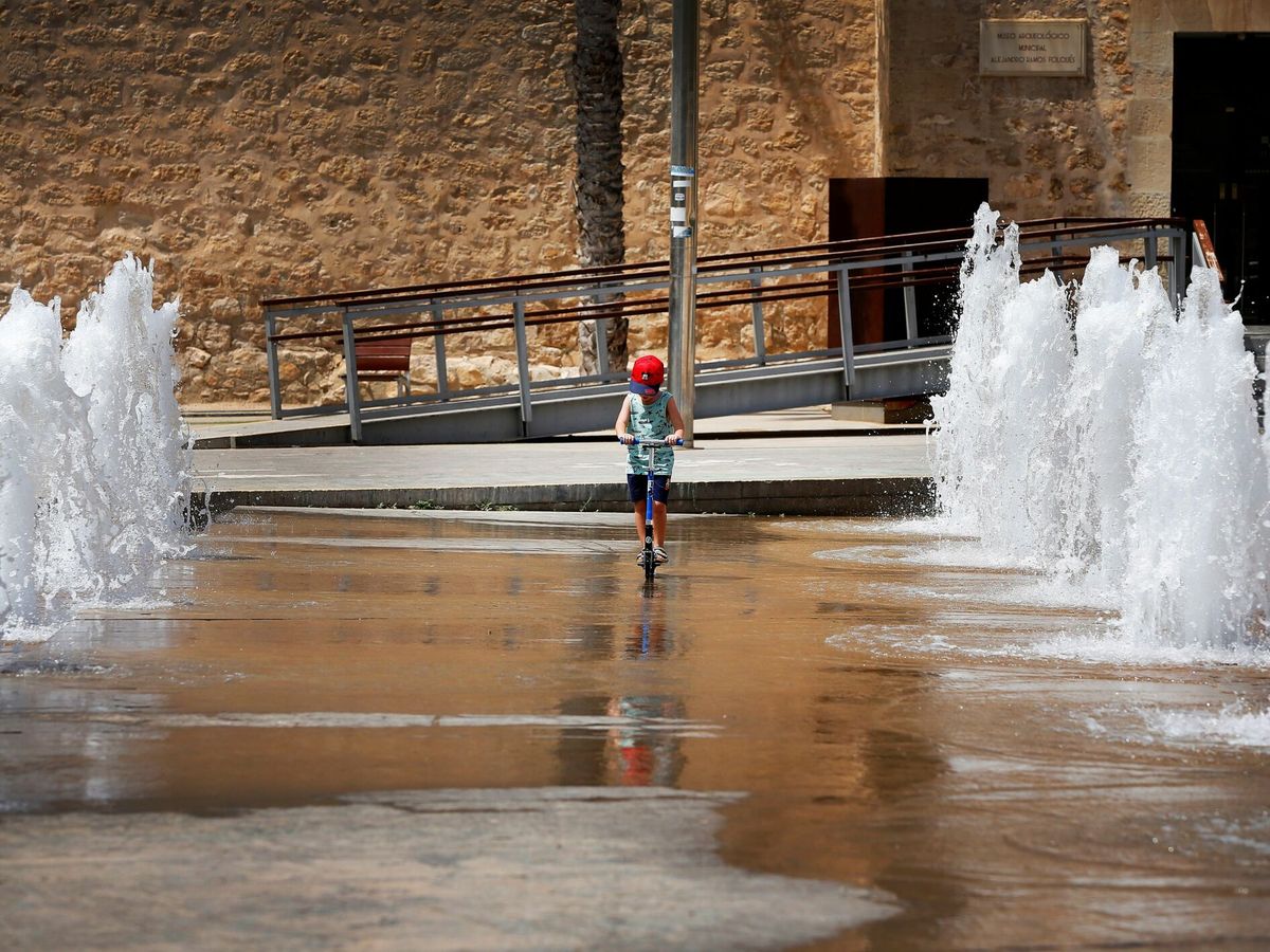 Foto: Un niño patina entre chorros de agua en una fuente de Elche. (EFE/Manuel Lorenzo)