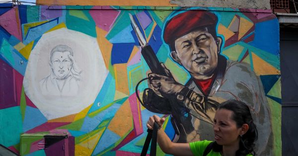 Foto: Una mujer pasa frente a un mural del presidente Hugo Chávez en Caracas, el 4 de febrero de 2019. (EFE)
