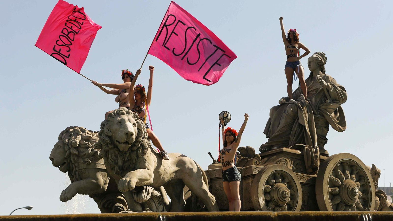 Foto: Cuatro activistas de Femen encaramadas sobre la fuente de Cibeles para protestar contra la ley mordaza. (EFE)
