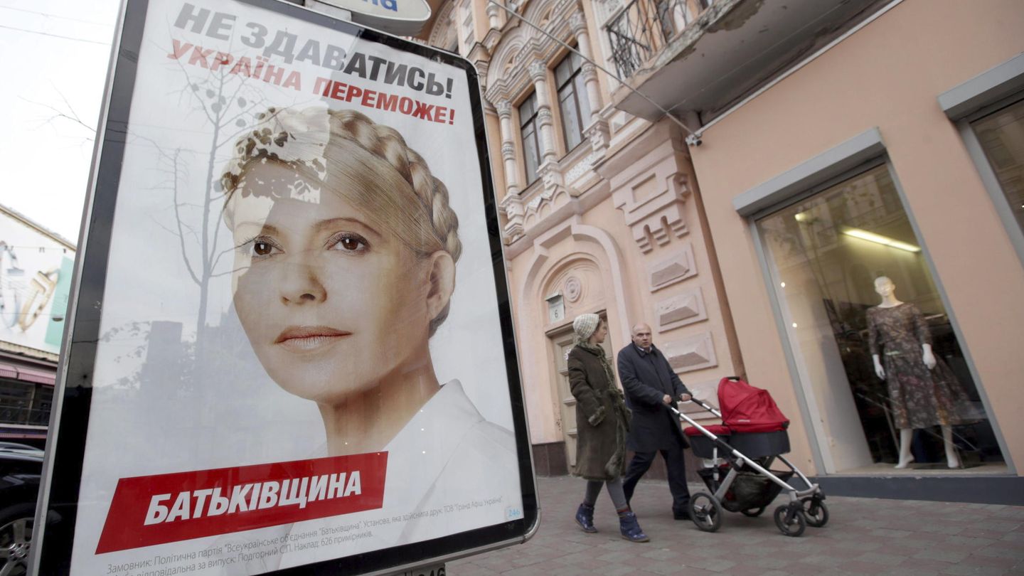 Dos personas caminan junto a un cartel con el retrato de la candidata electoral Yulia Timoshenko. (EFE/Tatyana Zenkovich)