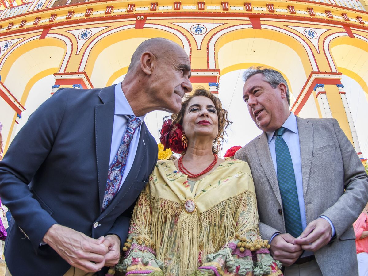 Foto: María Jesús Montero, entre Antonio Muñoz y Juan Espadas, delante de la portada de la Feria de 2023. (EFE/Raúl Caro)