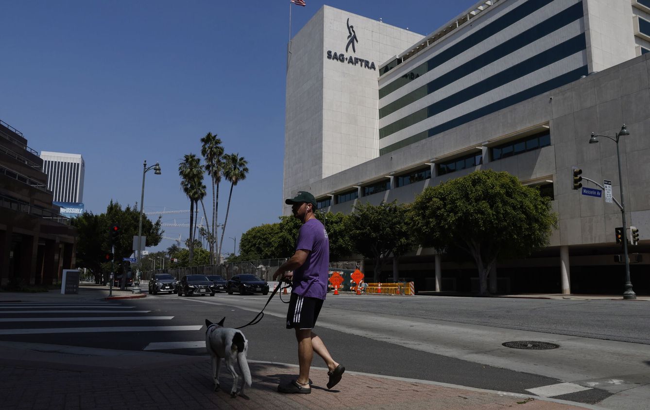 Un hombre pasea a su perro frente a la sede de SAG-AFTRA en Los Ángeles. (EFE/Caroline Brehman) 