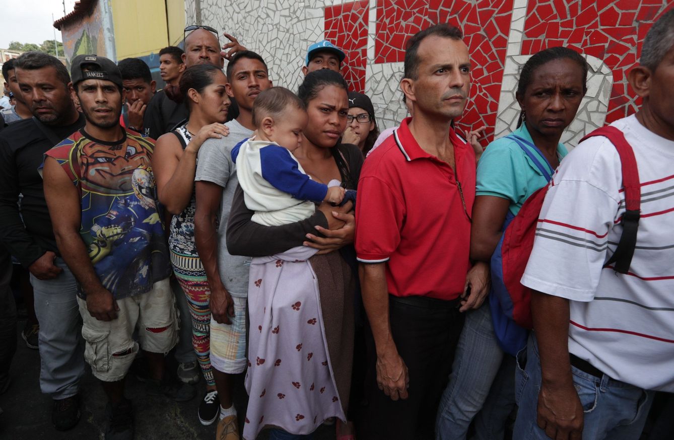 Un grupo de personas hace fila para recibir elementos del primer cargamento de ayuda humanitaria de la Cruz Roja que llegó este martes a Caracas. (EFE)