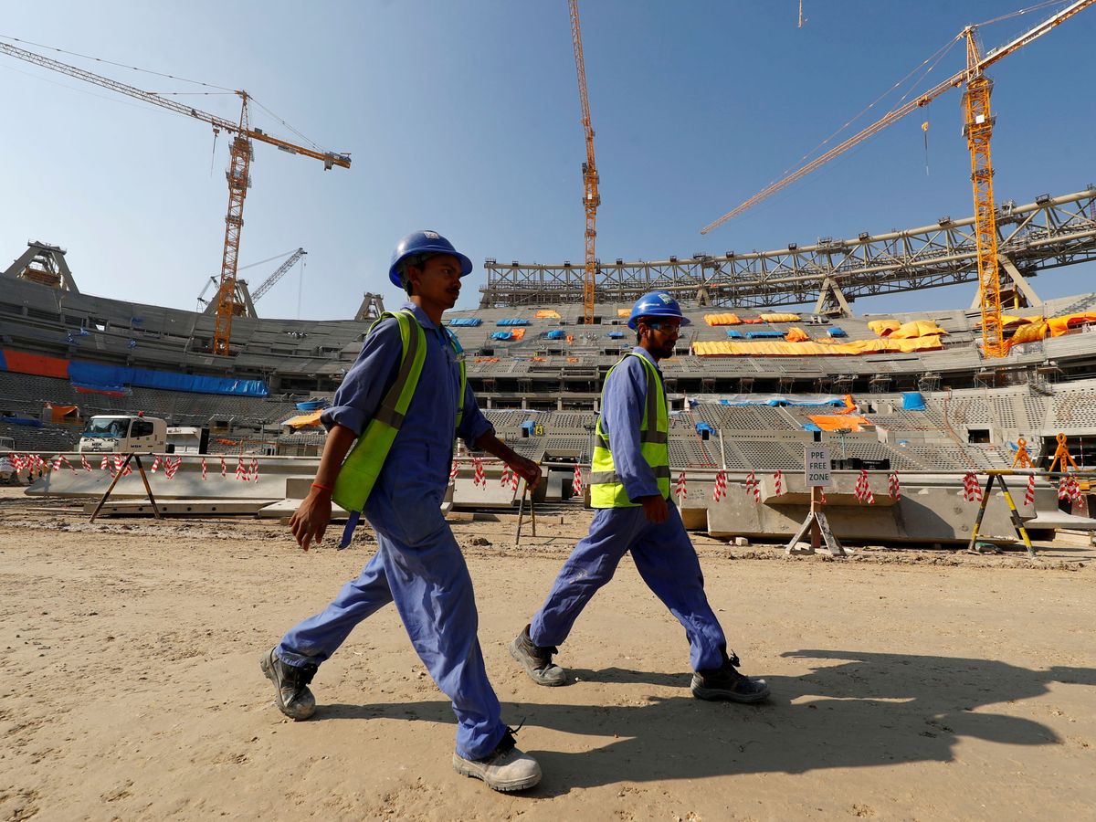 Foto: Dos trabajadores caminan entre las obras de un estadio de fútbol en Doha. (Reuters)