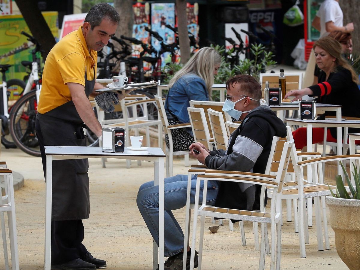 Foto: Un camarero atiende a un cliente con mascarilla antes de la declaración del estado de alarma (EFE)