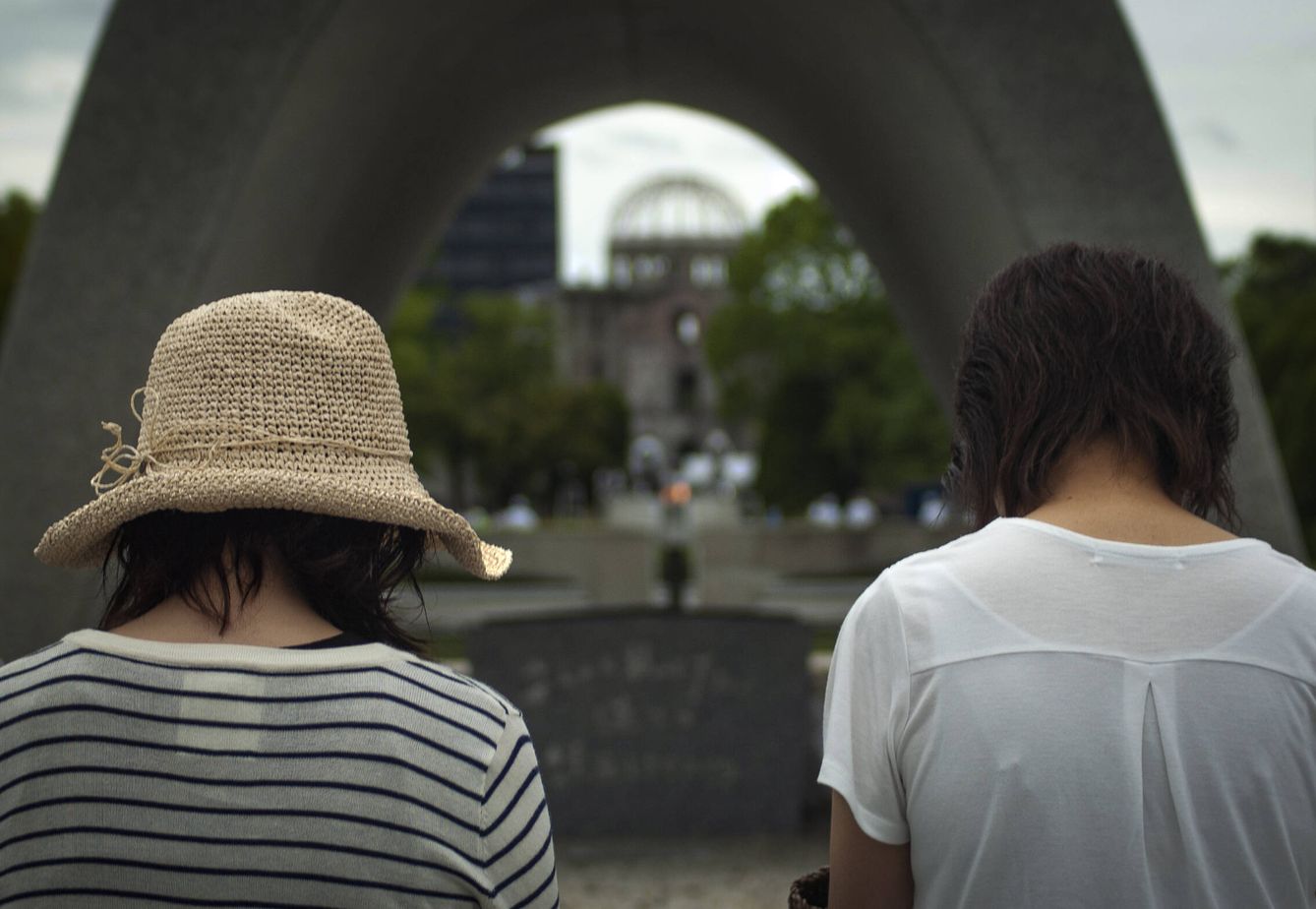 Dos jovenes, rezando ante el cenatofio de Hiroshima en memoria de las víctimas de la bomba atómica. TOÑI GUERRERO