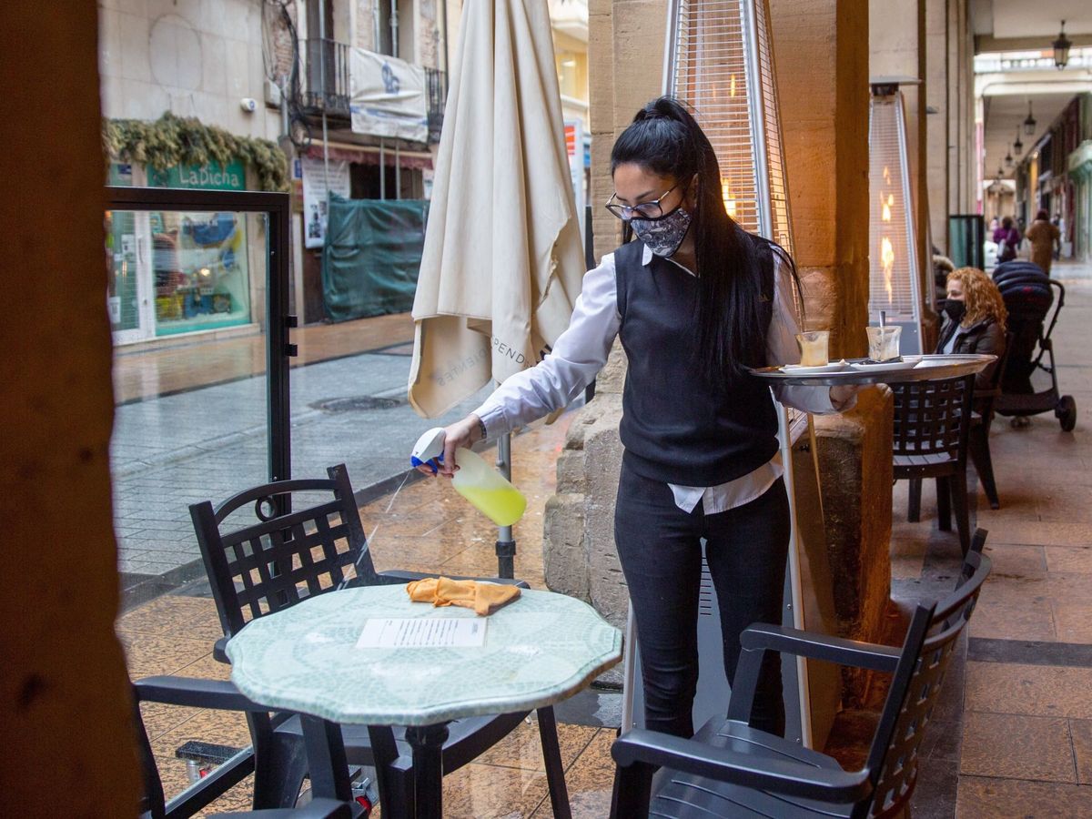 Foto: Camarera de un bar en la céntrica calle Portales de Logroño, limpia la mesa. (Raquel Manzanares/EFE)