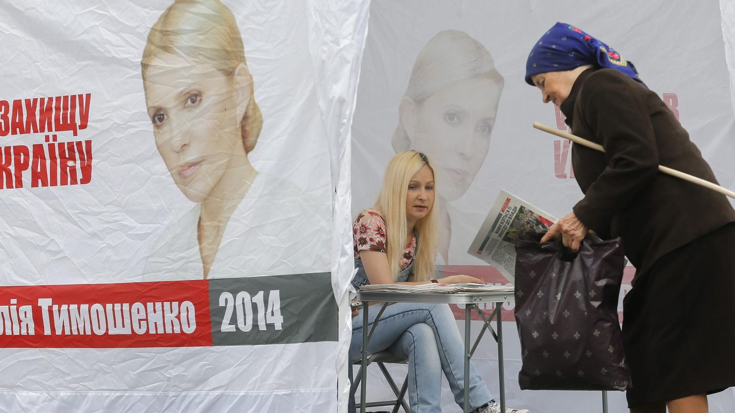 Una mujer recoge propaganda electoral de la candidatura de Timoshenko. (Efe)
