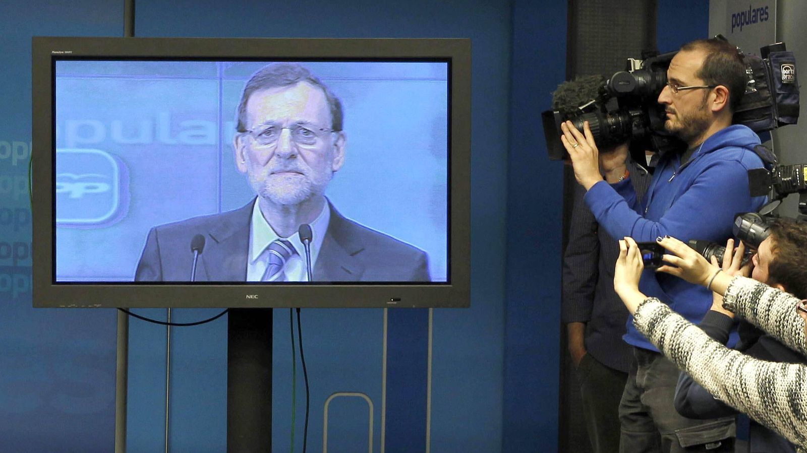 Foto: Los cámaras de los medios graban un monitor de la sala de prensa del PP tras ser informados de que la intervención de Rajoy sería solo a través de la pantalla de plasma y sin responder a las preguntas de los periodistas. EFE