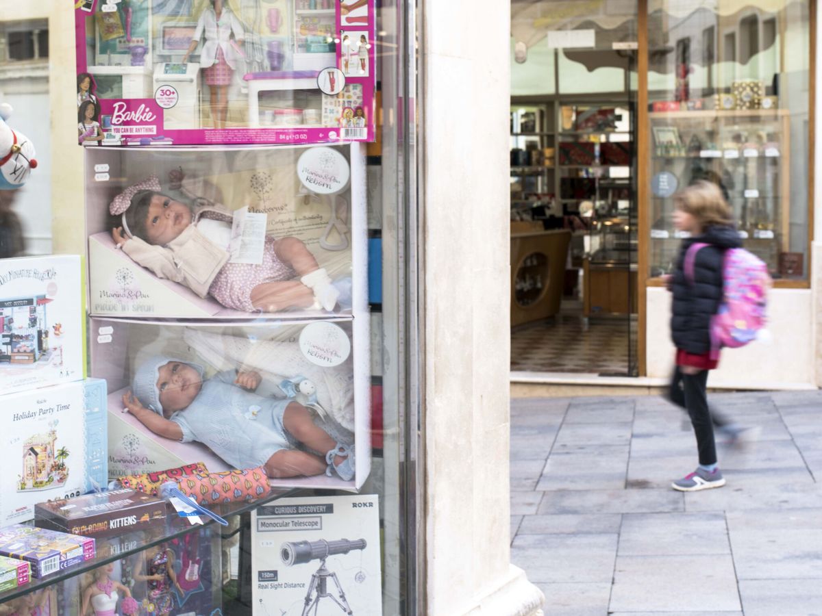 Foto: Una menor camina por la calle junto al escaparate de una tienda de juguetes. (EFE/David Arquimbau Sintes)