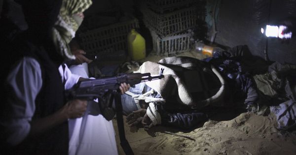 Foto: Un beduino armado custodia a un inmigrante ilegal en el norte del Sinaí, antes de introducirle de forma clandestina en Israel. (Reuters)