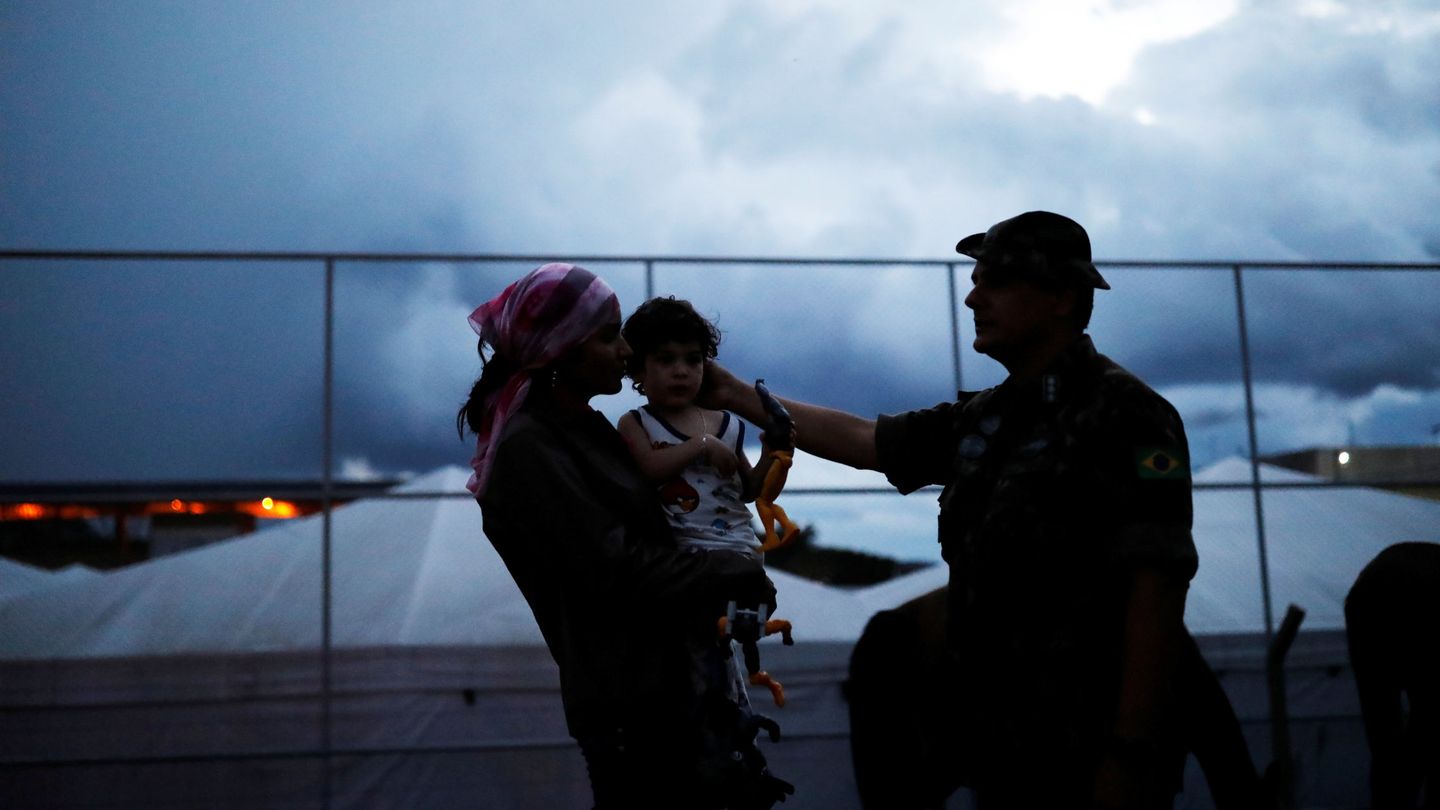 Un teniente del ejército brasileño habla con una venezolana y su hijo tras comprobar sus pasaportes en el paso fronterizo, el 19 de agosto de 2018. (Reuters)