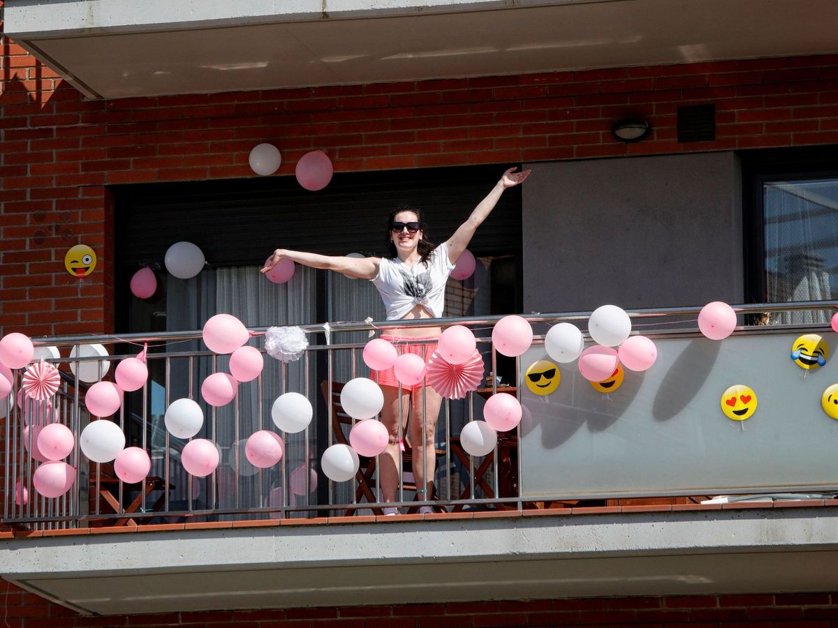 Foto: Una mujer de Barcelona sale a su balcón, adornado con globos, como si de una fiesta se tratase (EFE)
