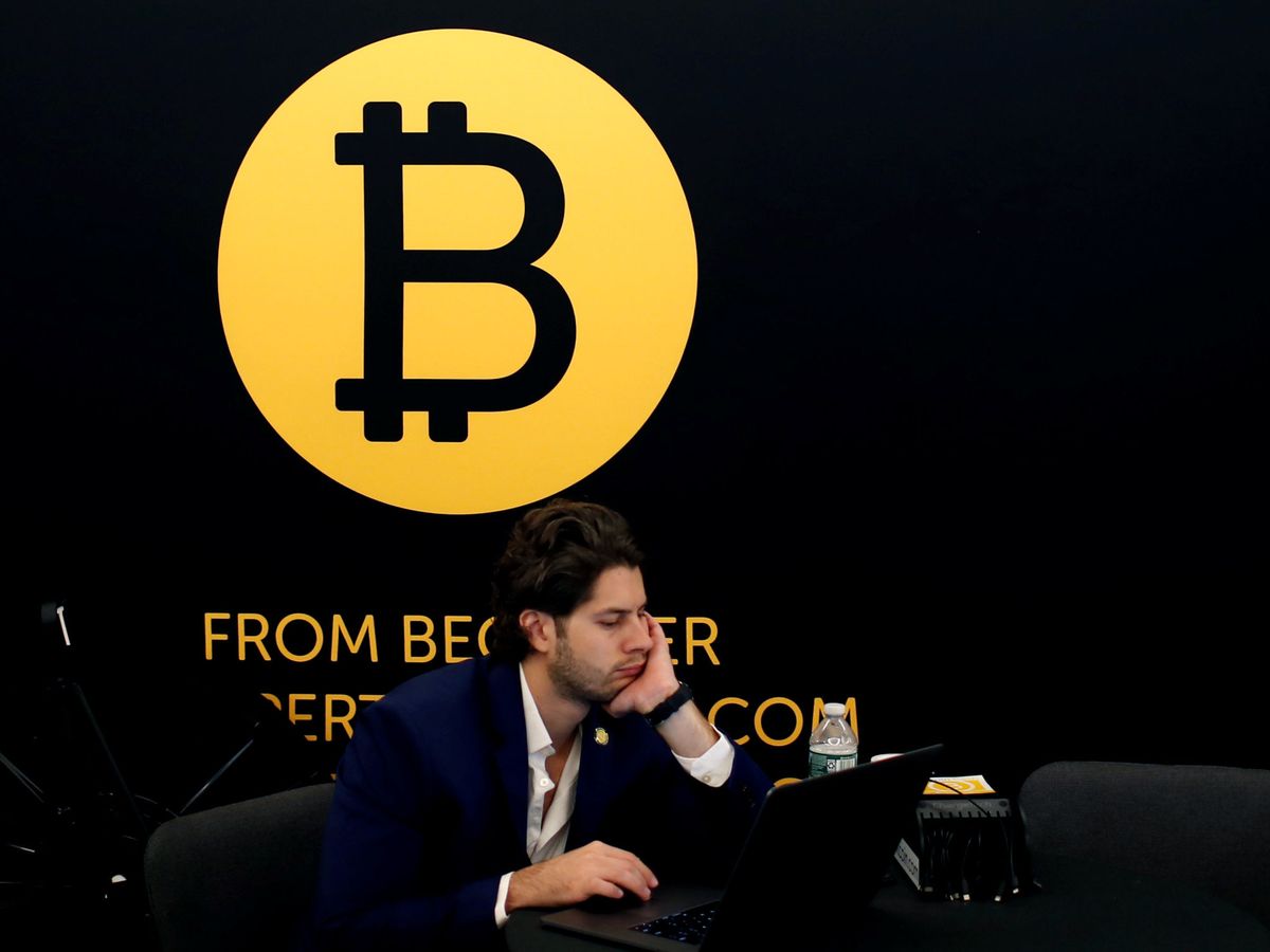 Foto: Un hombre trabajando frente al logo de Bitcoin. (Reuters/Mike Segar)
