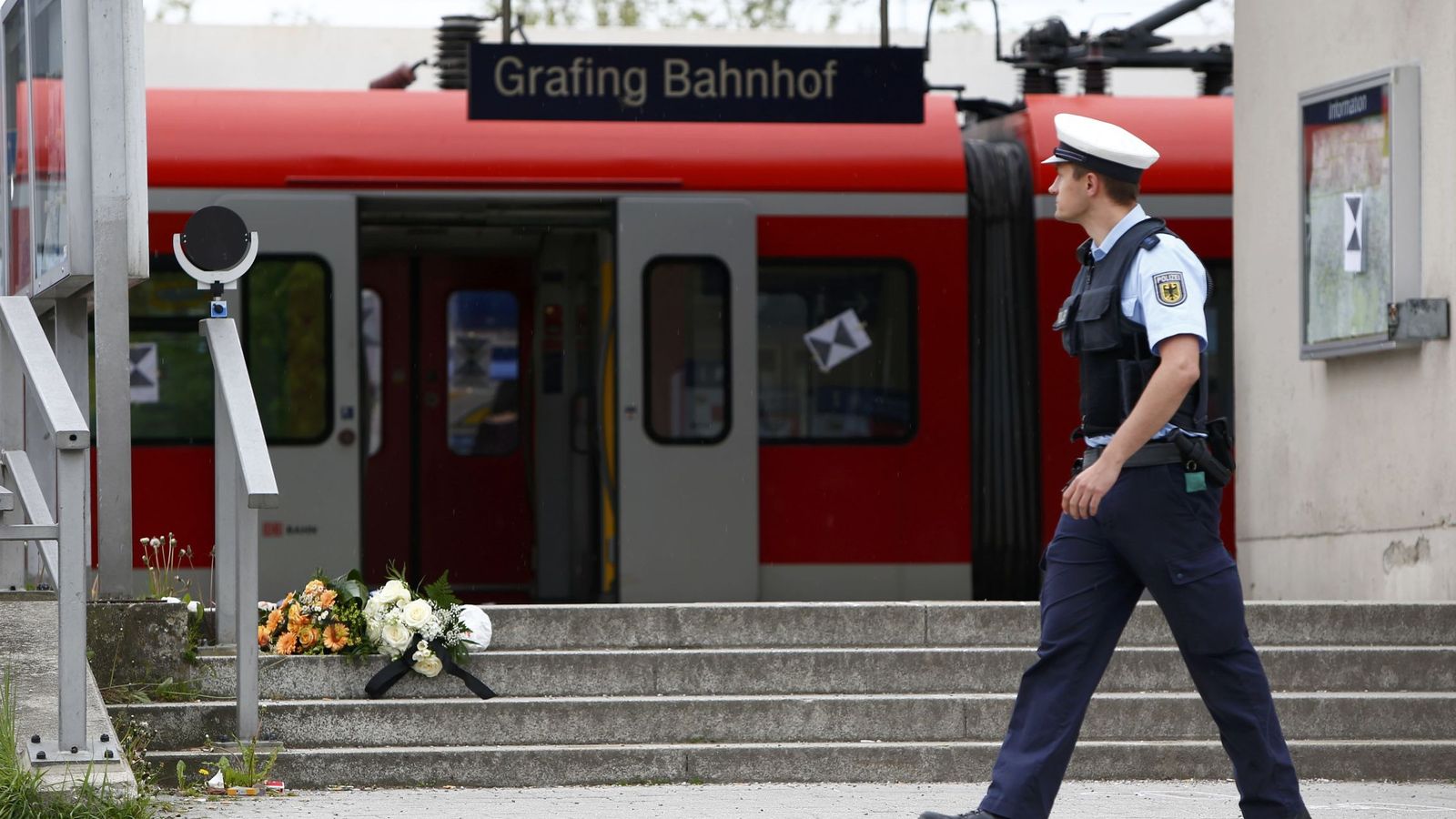 Foto: Un policía pasa delante de unas flores depositadas tras un ataque a cuchillo en un tren al sureste de Múnich, en mayo de 2016. (Reuters)