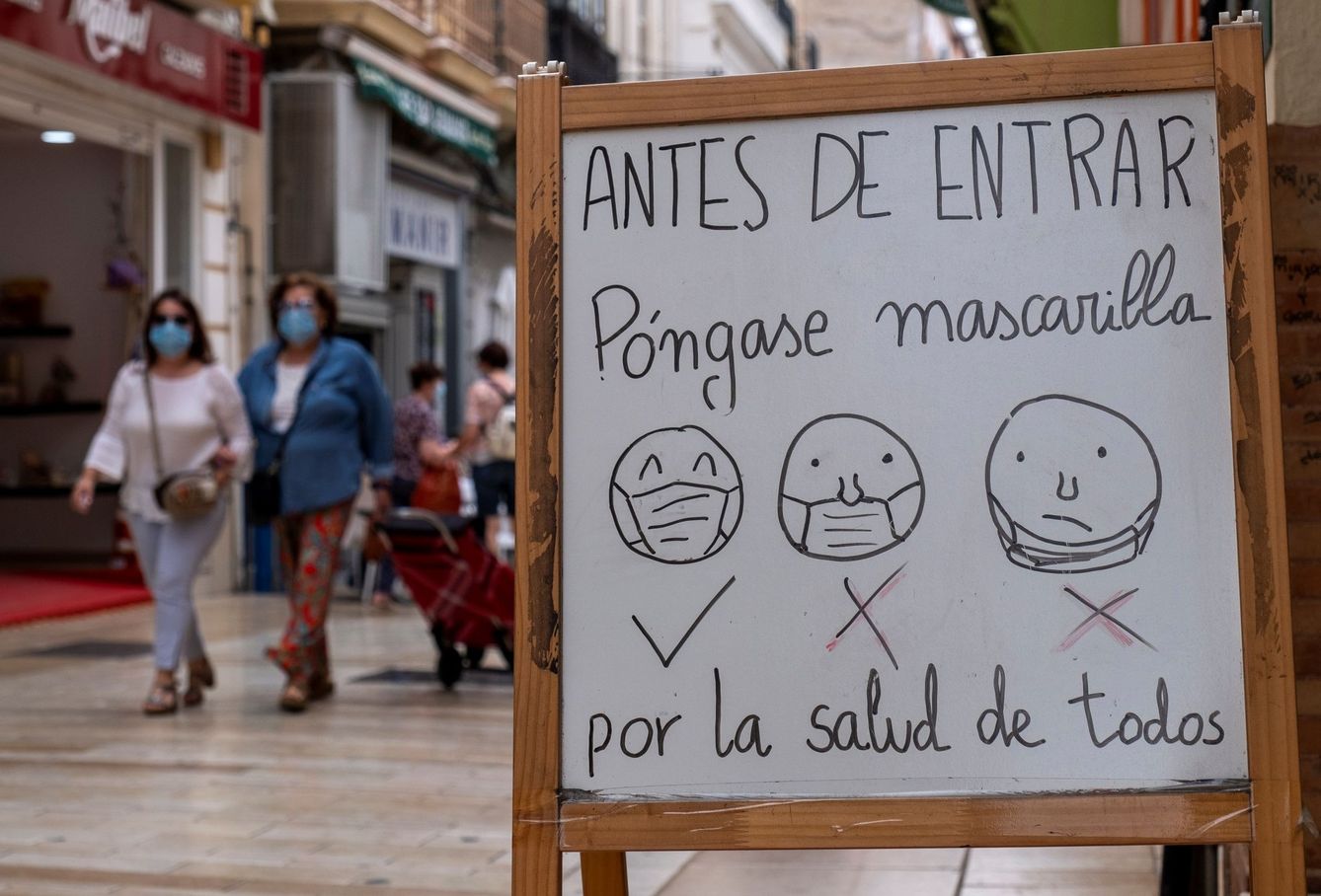 Un cartel a la entrada de un establecimiento de Huelva informa a los clientes de la obligatoriedad del uso de mascarillas. (EFE)