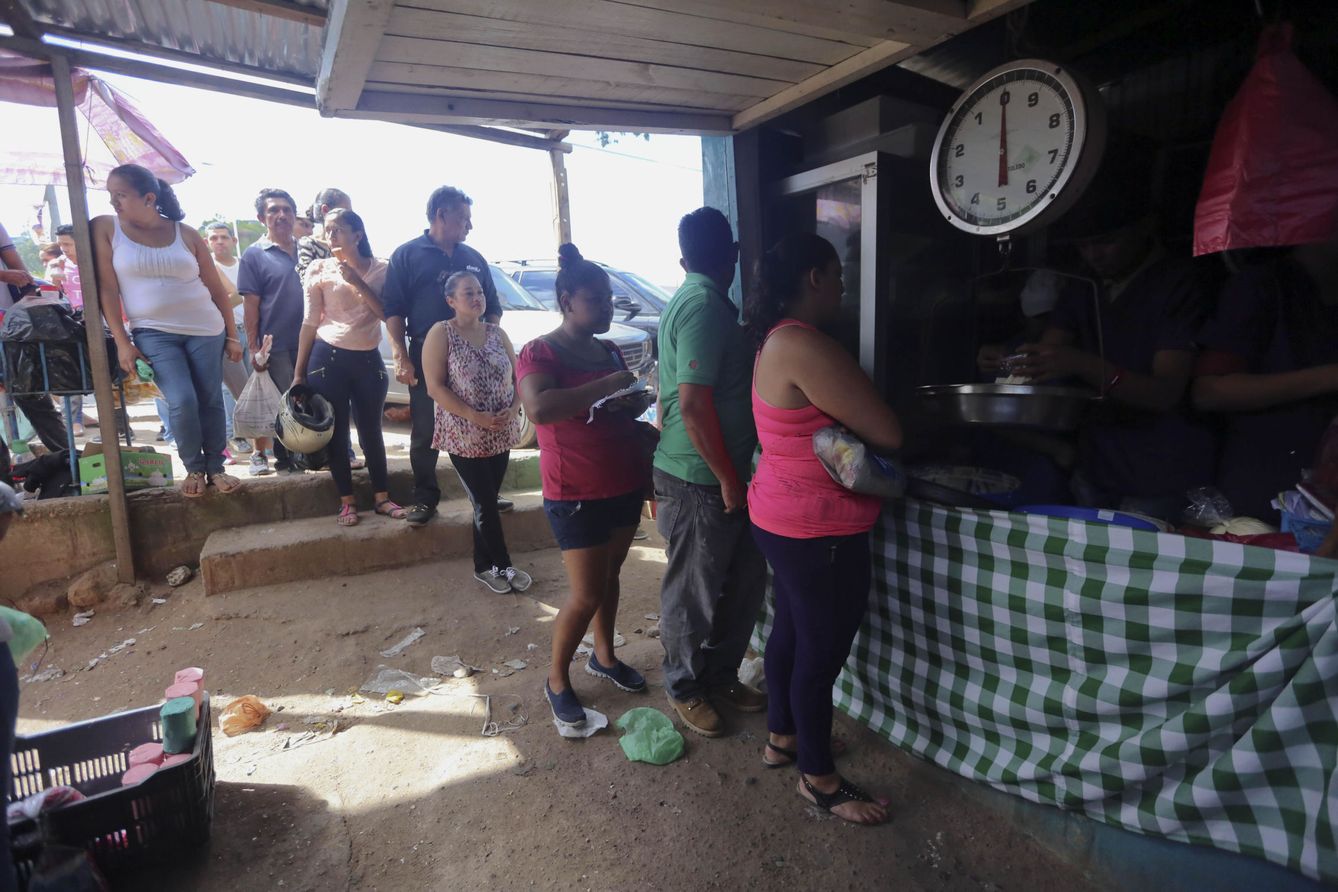 Ciudadanos hondureños guardan una fila para comprar alimentos en un feria de agricultores. (EFE)