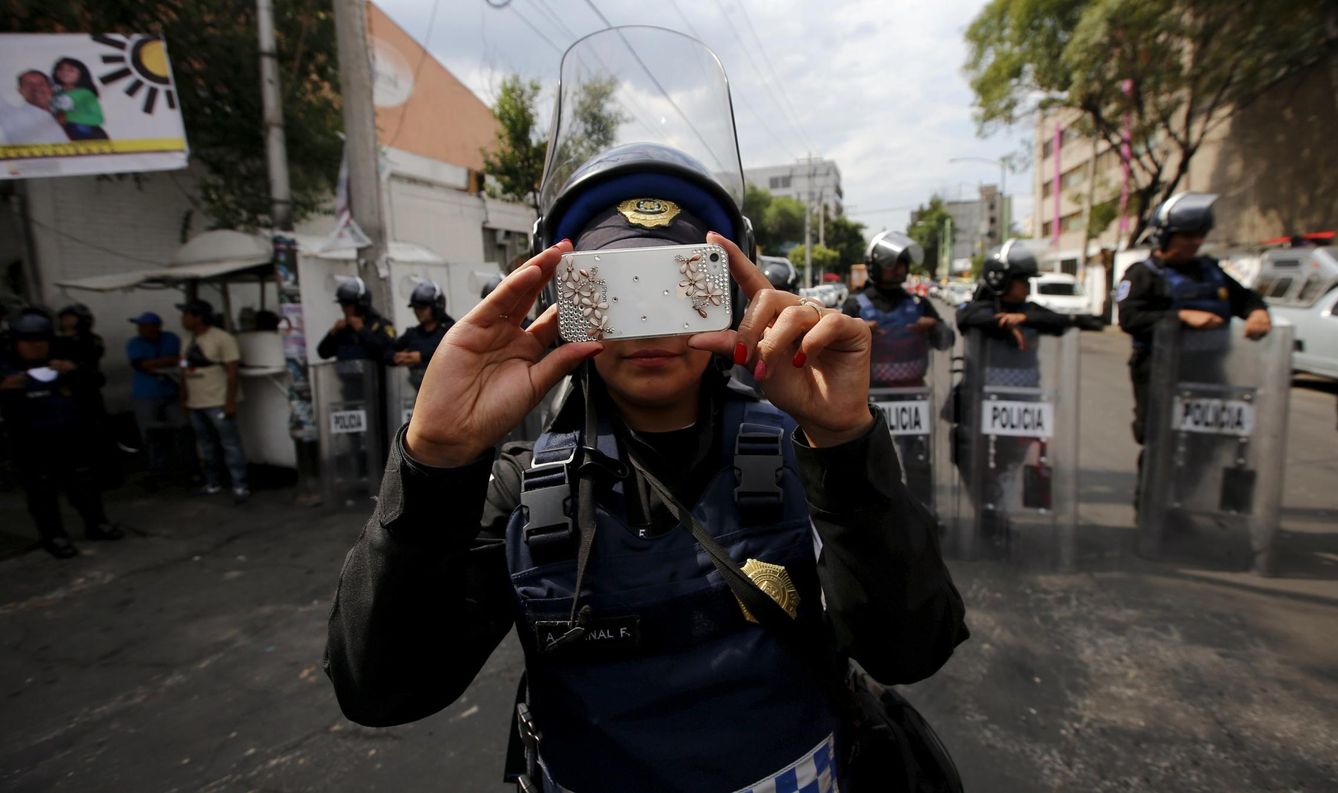 Foto: Una policía hace fotografías a manifestantes durante una protesta por la desaparición de 43 estudiantes en Iguala. (Reuters)