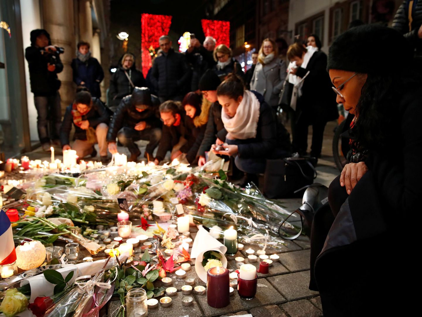 Ciudadanos franceses encienden velas y depositan flores en el lugar del atentado, el 13 de diciembre de 2018. (Reuters)