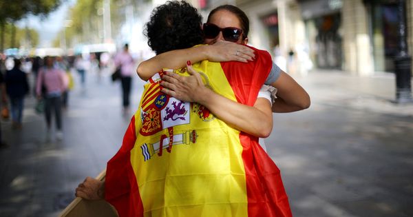 Foto: Un joven con la bandera de España reparte "abrazos gratis" en Barcelona. (Reuters)
