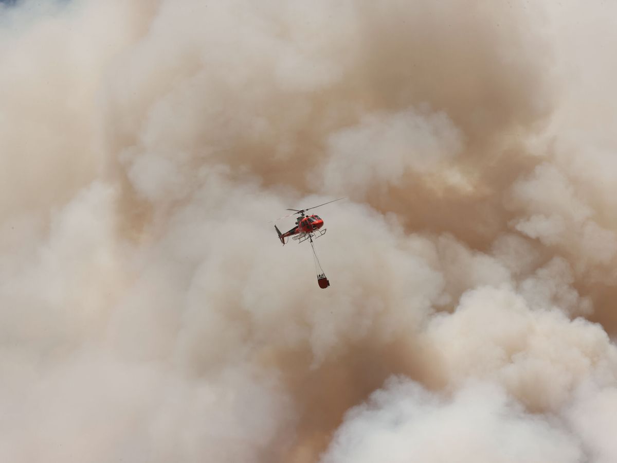 Foto: Un helicóptero trabaja en extinguir el incendio en Olloki. (EFE/Jesús Diges)