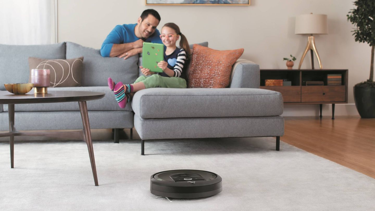 Una pobre Roomba, olvidada en mitad del salón mientras la familia se divierte con una 'tablet' de 2014.